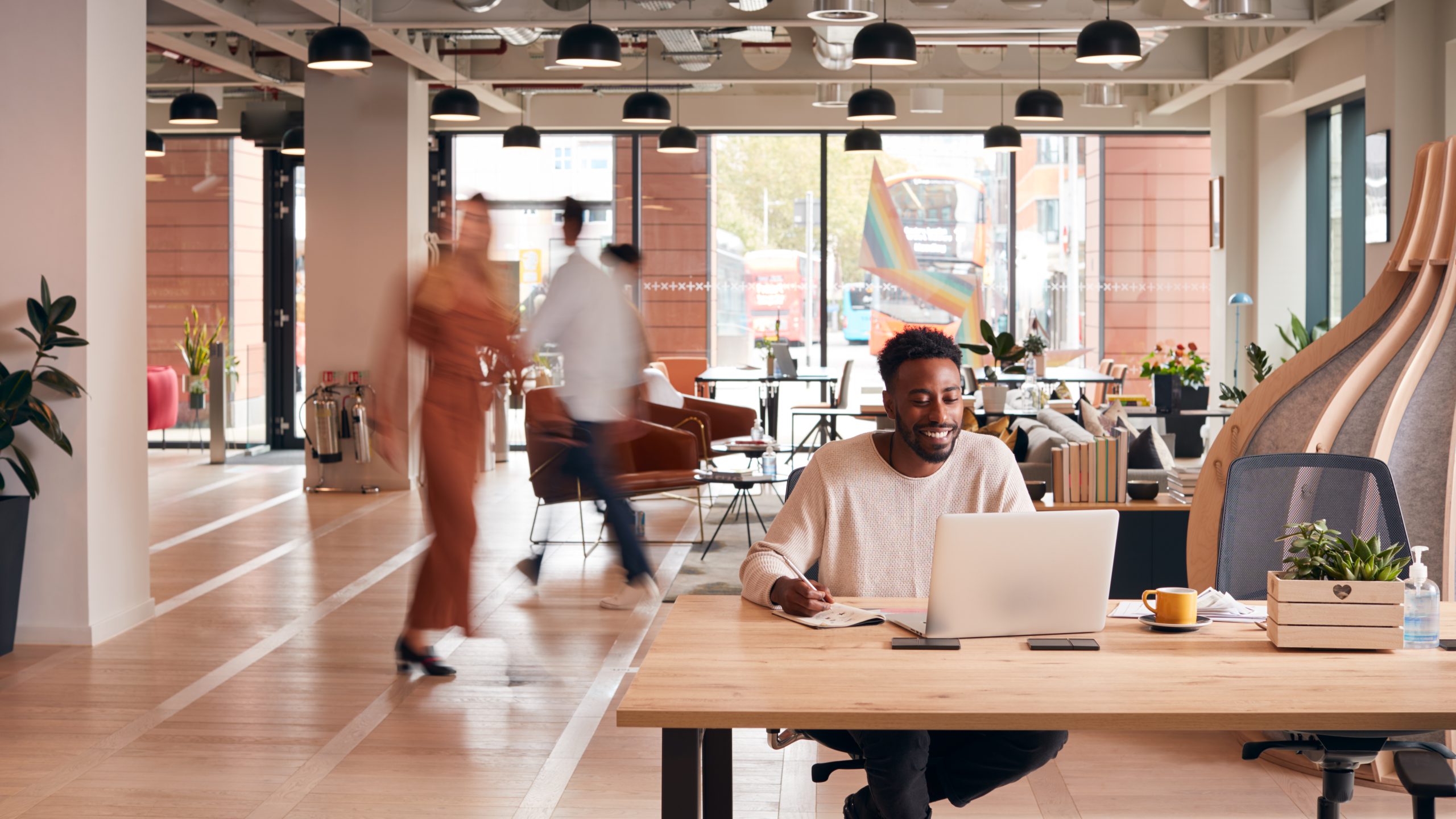 Businessman,Sitting,At,Desk,Writing,In,Notebook,In,Modern,Open